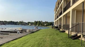 A building with a grassy lawn and a dock extending into a body of water.
