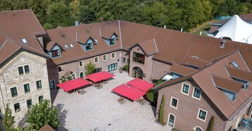 A multi-story building with a courtyard featuring red umbrellas and outdoor seating.