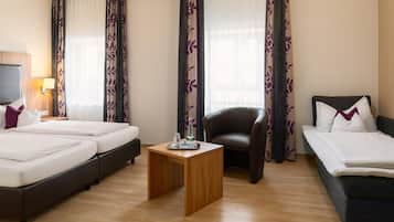 Ein Hotelzimmer mit zwei Betten, einem Sofa, einem Holztisch und einem Sessel.