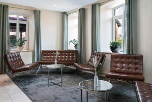 A modern lounge area with leather sofas, a glass coffee table, and potted plants.