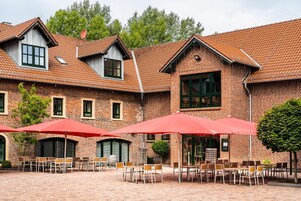 A brick building with a courtyard featuring outdoor seating and umbrellas.
