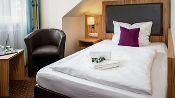 Une chambre d’hôtel avec un lit, une chaise, une table de chevet et une lampe.