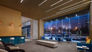 Eine moderne Lobby mit einer Rezeption, einer Sitzecke und großen Fenstern mit Blick auf die Straße.