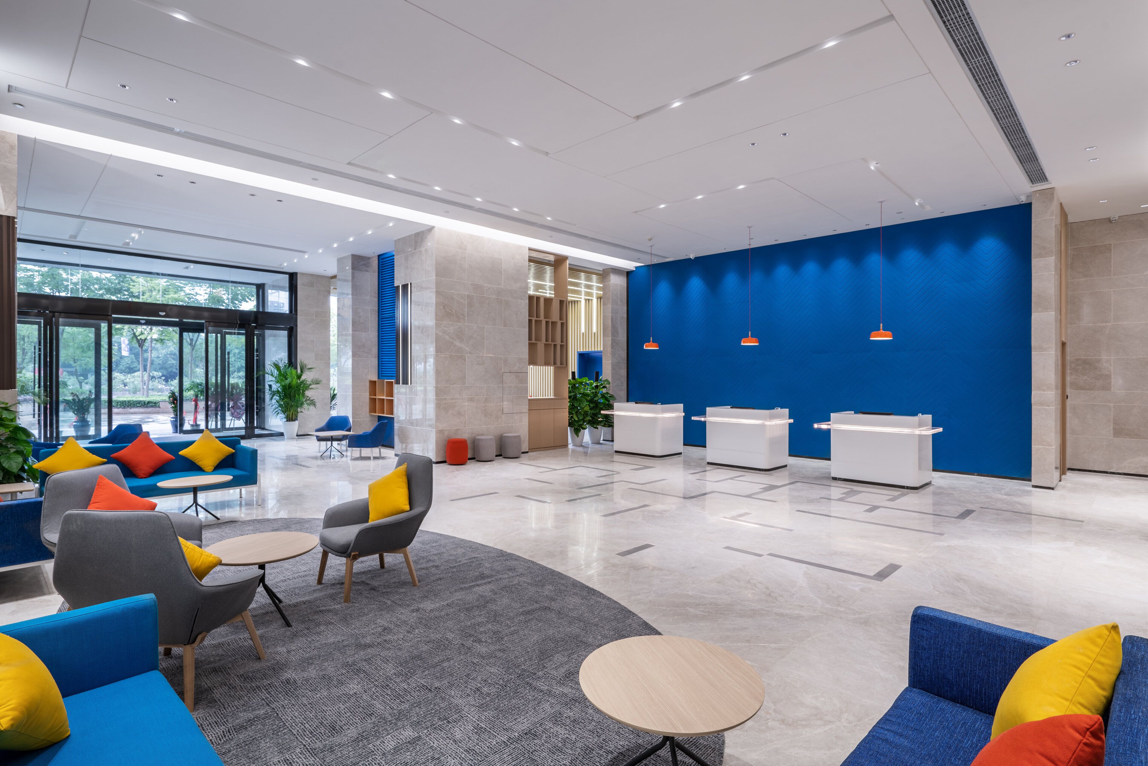 A modern lobby with seating areas, reception desks, and a large blue wall.