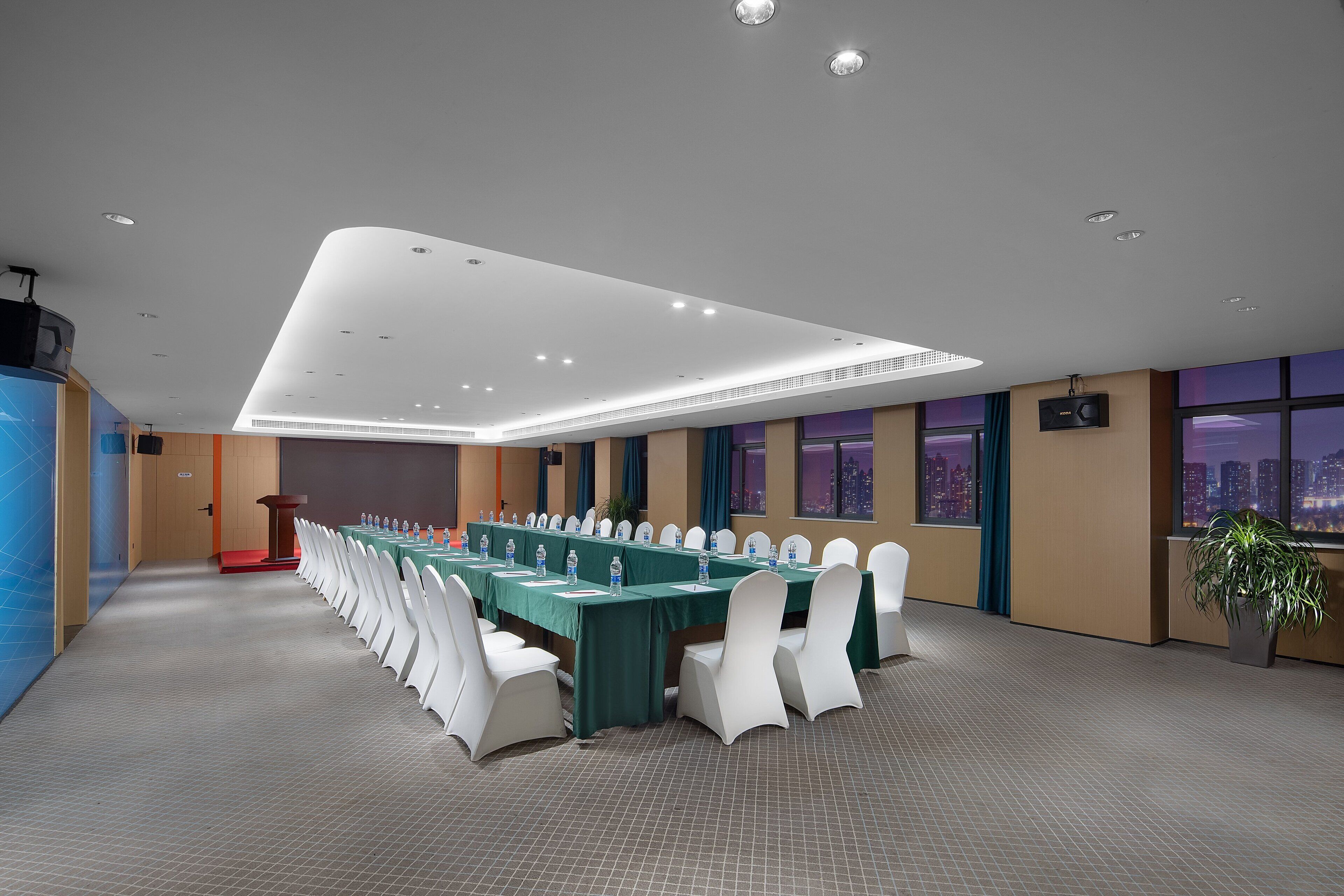 Une salle de conférence dotée d’une longue table, de chaises blanches et offrant une vue sur la ville grâce à de grandes fenêtres.