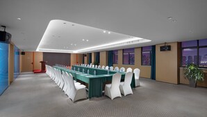 Ein Konferenzraum mit langem Tisch, weißen Stühlen und Blick auf die Stadt durch große Fenster.