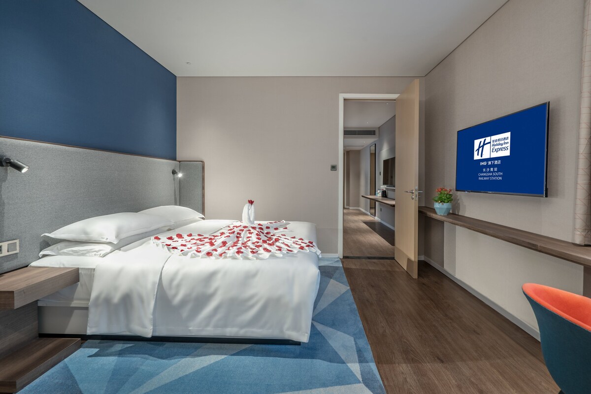 Una habitación de hotel moderna con una cama, televisión, escritorio y una silla.