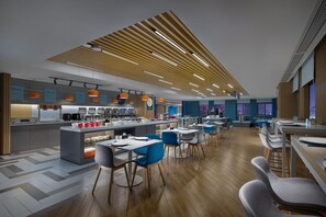 Un restaurante moderno con una isla central, sillas azules y grises, y techo de madera.
