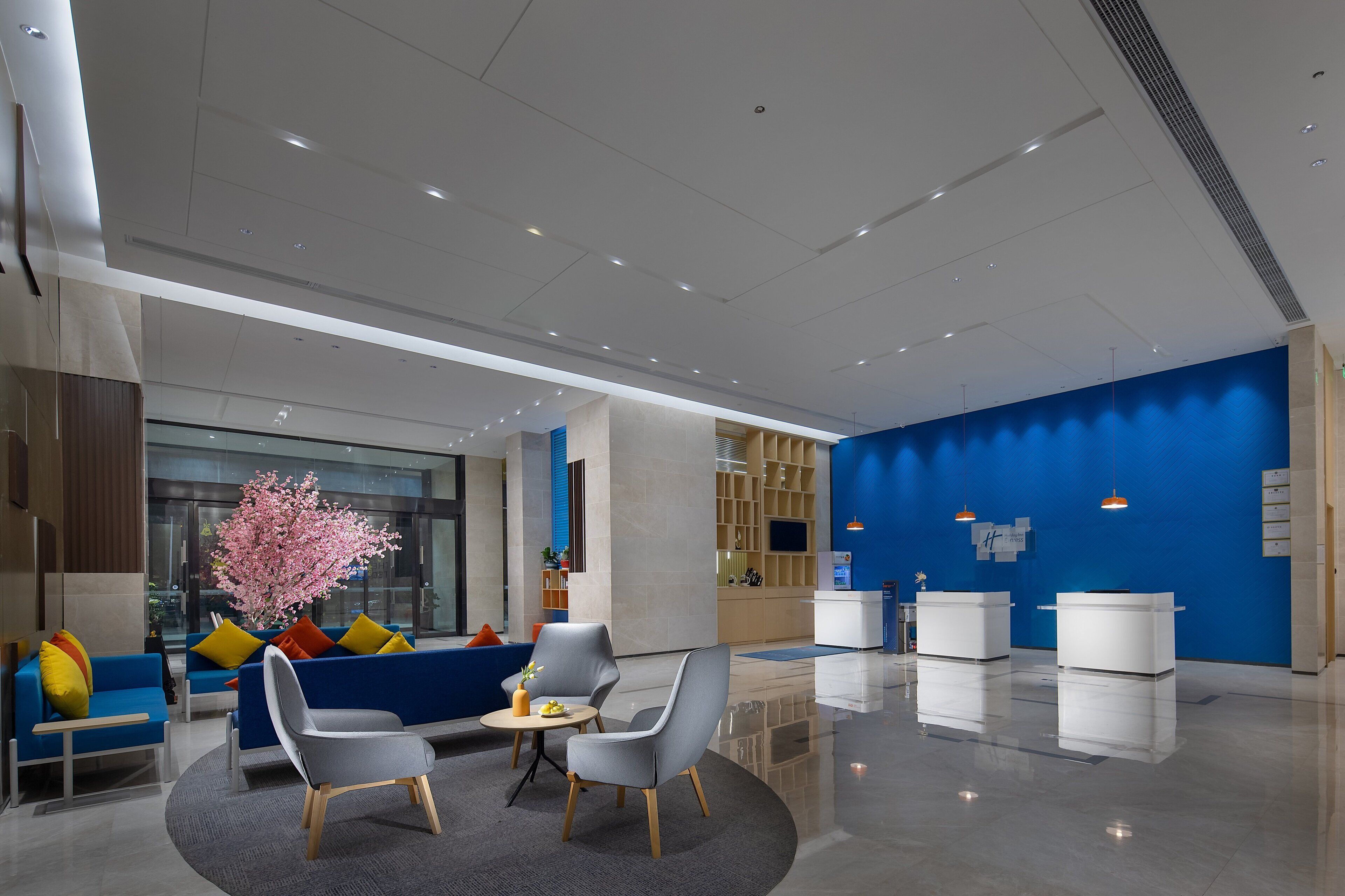 A modern lobby with seating areas, a reception desk, and a blue accent wall.