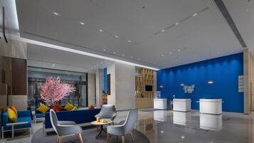A modern lobby with seating areas, a reception desk, and a blue accent wall.