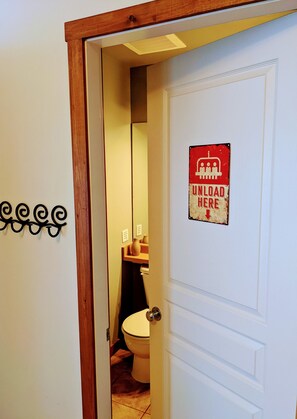 Une salle de bain équipée de toilettes, d’un miroir et d’un panneau indiquant : « Décharger ici ».
