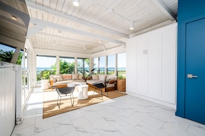 A spacious room with a large window overlooking the sea, a blue door, and a white ceiling. - (3 Nt Min) Lakefront Home With Private Beach and Sauna!! (Lakeside)
