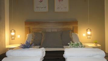 A neatly made bed with pillows, two wall-mounted light fixtures, and two framed artworks on the wall.