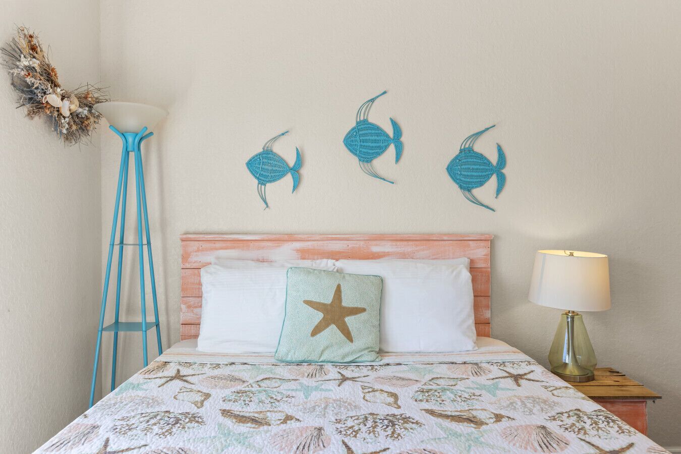 A bedroom with a bed, a nightstand, a lamp, and wall art of fish.