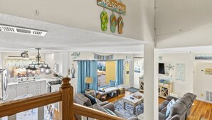 A spacious living area with a kitchen, dining area, and a balcony. - Seaside Serenity Oceanfront Pool Home (Ormond Beach)