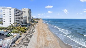 A beachside hotel with multiple floors, a sandy beach, and the ocean. - Seaside Serenity Oceanfront Pool Home (Ormond Beach)