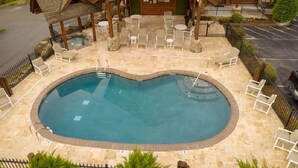 Un área de piscina con una piscina circular, sillas de descanso y una zona de estar cubierta.