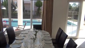 A dining area with a table set for six, large windows, and a view of a swimming pool.