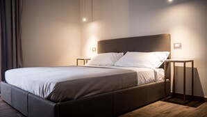 A modern bedroom with a large bed, two bedside tables, and a nightstand. - Toledo Class (Naples)