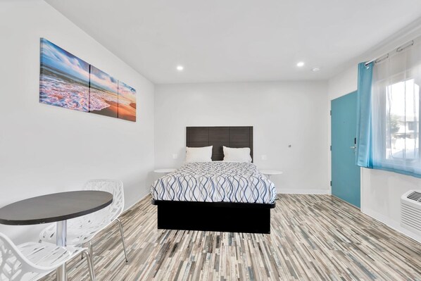 A modern bedroom with a bed, bedside tables, a small table, and chairs.