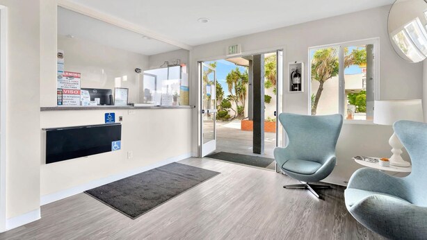 A reception area with a desk, chairs, and a large window. - Tradewinds Motel (Lakewood)