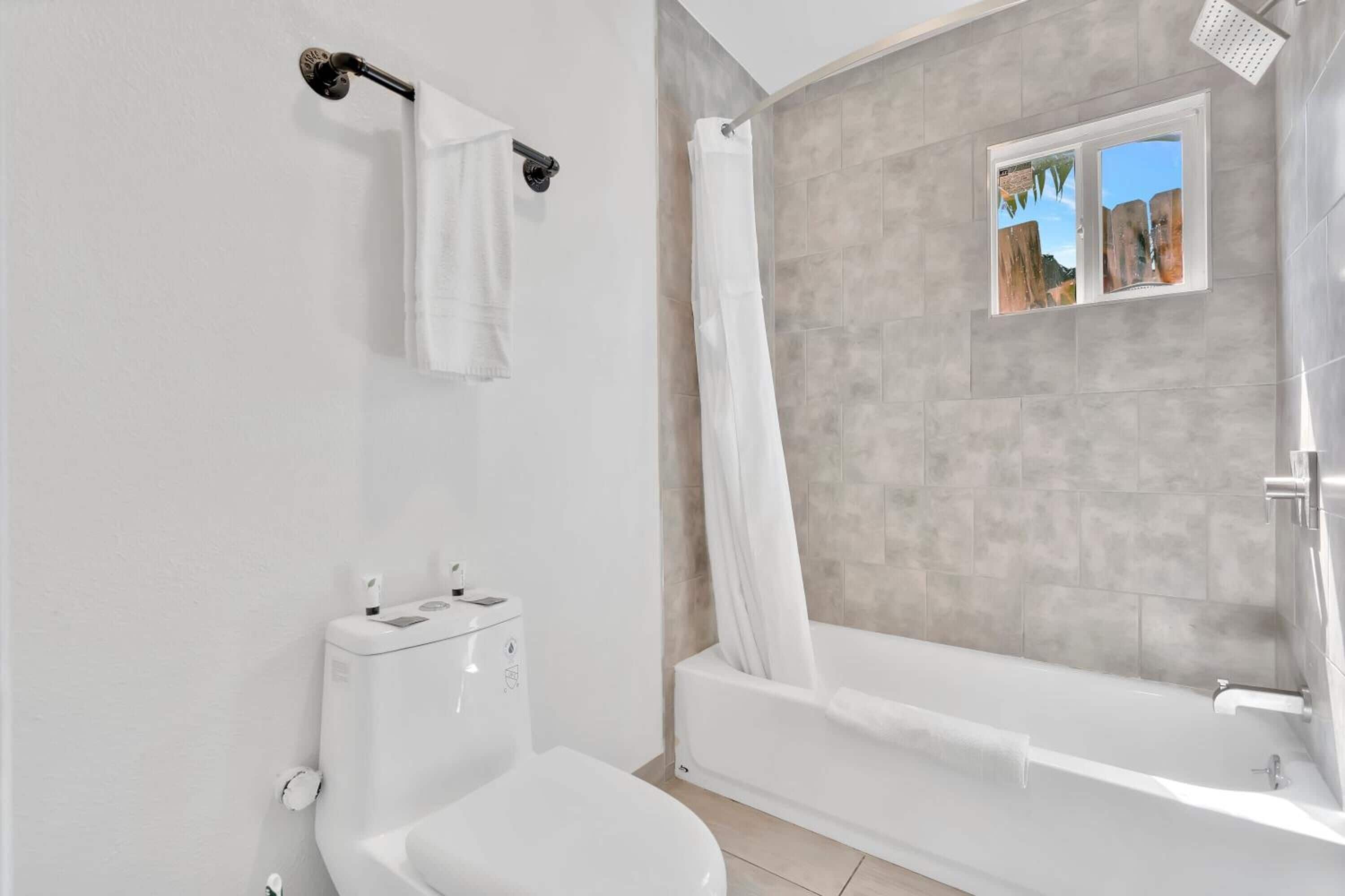 Ein modernes Badezimmer mit Toilette, Badewanne und Duschvorhang.