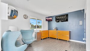 A modern room with a blue wall, a clock, a TV, and a cabinet. - Tradewinds Motel (Lakewood)