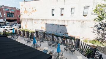 An outdoor patio area with tables and chairs, a brick wall, and a building in the background.