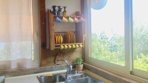 Eine kleine Küche mit Fenster, Spüle, Herd und Regalen mit Geschirr.