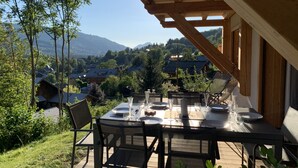 An outdoor dining area with a table set for four, overlooking a scenic village and mountains. - A gorgeous 3 bed apartment, 3 minutes walk from the centre of Samoëns (Samoëns)