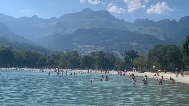 A beach with people swimming and walking on the shore, surrounded by mountains. - A gorgeous 3 bed apartment, 3 minutes walk from the centre of Samoëns (Samoëns)