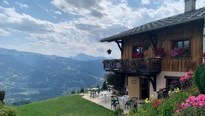 A chalet with a balcony, outdoor seating, and a mountainous backdrop. - A gorgeous 3 bed apartment, 3 minutes walk from the centre of Samoëns (Samoëns)