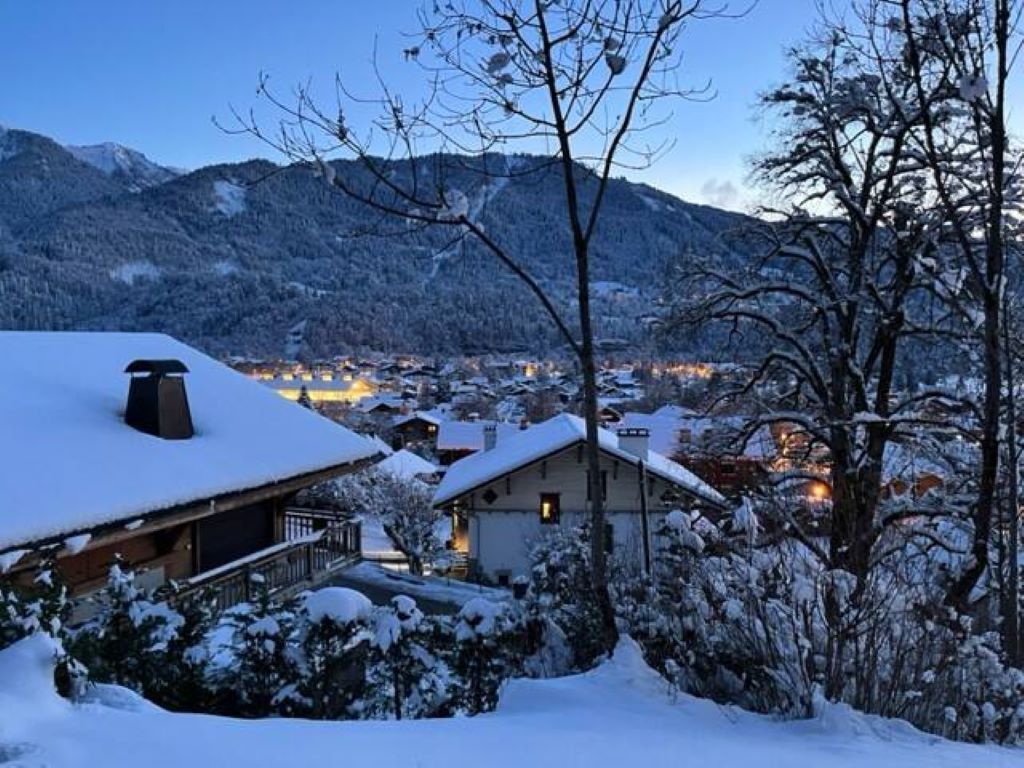Ein verschneites Dorf mit Gebäuden und Bergen im Hintergrund.