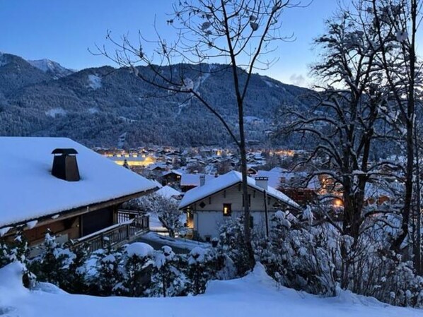 Un village enneigé, avec des bâtiments et des montagnes en arrière-plan.