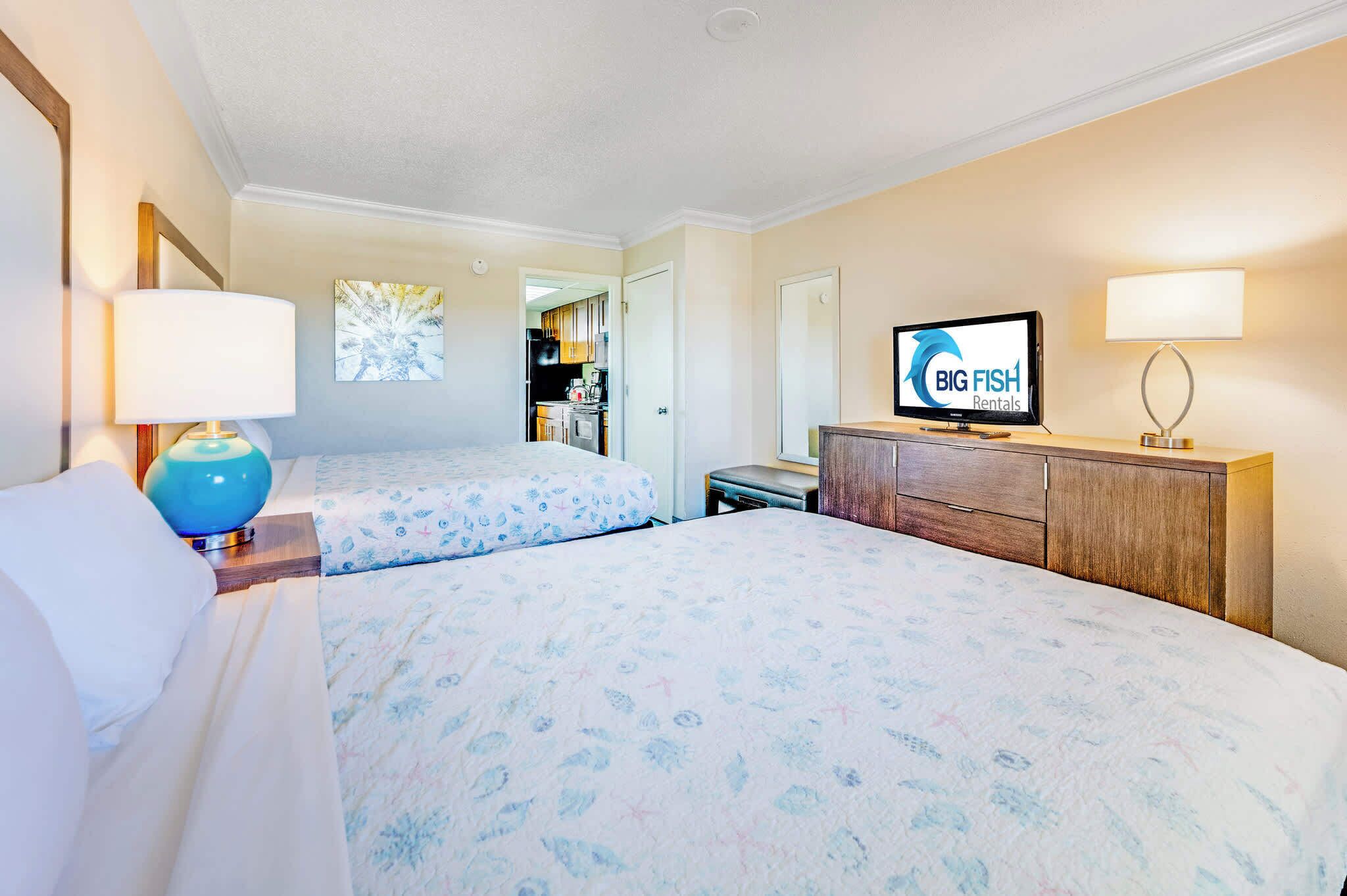 A hotel room with two beds, a TV, a desk, and a cabinet.