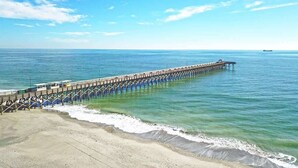 A pier extending into calm waters with a clear sky.