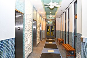 Guests can sit and relax on benches along this stylish corridor, featuring patterned tiles and ceiling fans.