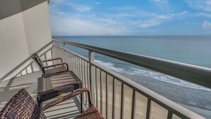 A balcony with wicker chairs overlooking the ocean.