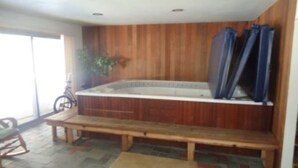 A hot tub with wooden paneling, a bench, and a bicycle. - Expansive Lakehouse with Jacuzzi (Argyle)