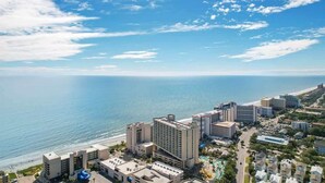 A coastal hotel complex with multiple buildings, a beach, and a clear sky. - Sand Dunes Resort North Tower, 17th Floor, Pools! (Myrtle Beach)