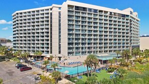A large, multi-story hotel with a pool area and sun loungers. - Sand Dunes Resort North Tower, 17th Floor, Pools! (Myrtle Beach)