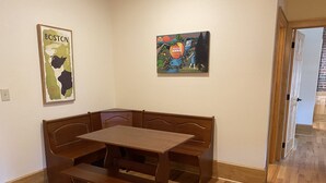 Un coin repas avec une table et un banc en bois, deux tableaux accrochés au mur et un plancher en bois.
