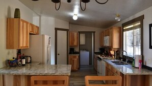Une cuisine dotée de meubles en bois, d’un plan de travail en marbre et d’un îlot central avec deux chaises.