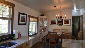 Une cuisine avec une table à manger, des chaises, un lustre et des tableaux encadrés accrochés au mur.