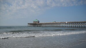 Un muelle que se adentra en el agua, con un pequeño edificio al final.