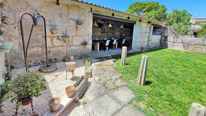 A rustic stone building with a tiled roof, outdoor seating area, and potted plants.