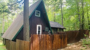A cabin with a triangular roof, wooden exterior, and a porch.