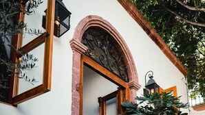 A woman entering a building with a wooden door and an arched entrance. - Clandestino Hotel Recreo - Adults Only (San Miguel de Allende)