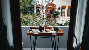 A table with a tray of breakfast items, a vase, and a cup, viewed from inside a room through an open door. - Clandestino Hotel Recreo - Adults Only (San Miguel de Allende)