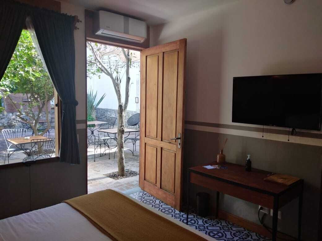 A hotel room with a bed, a desk, a TV, and a view of the outside patio area.